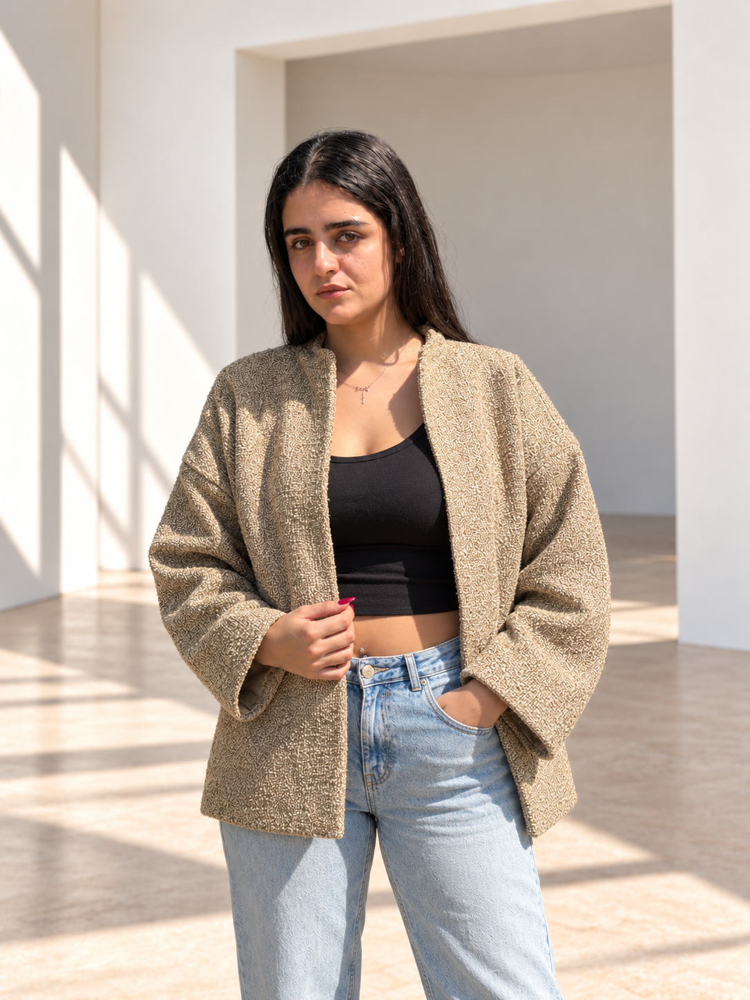 Front view of Fine R Studio beige bouclé jacket with an open front, dropped shoulders and wide sleeves.