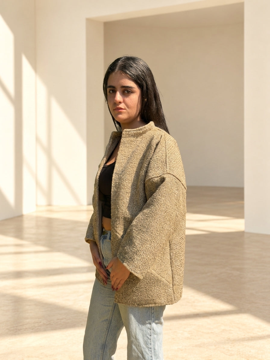 Fine R Studio beige bouclé art jacket worn open in a sunlit cream interior.