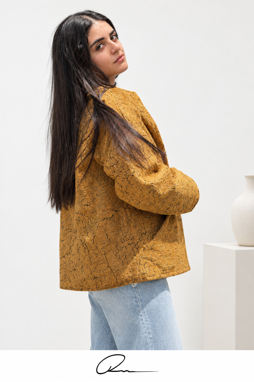 Close rear three-quarter view of Fine R Studio mustard textured jacket with the R signature below.