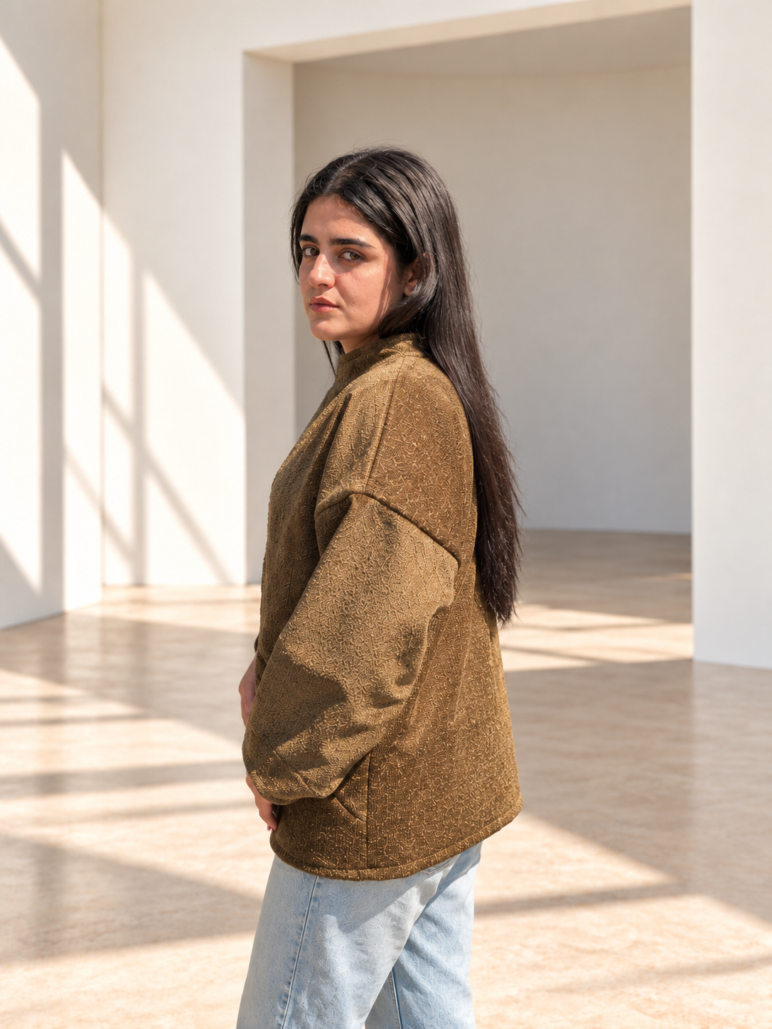 Side view of Fine R Studio olive art jacket showing subtle all-over texture and dropped shoulders.